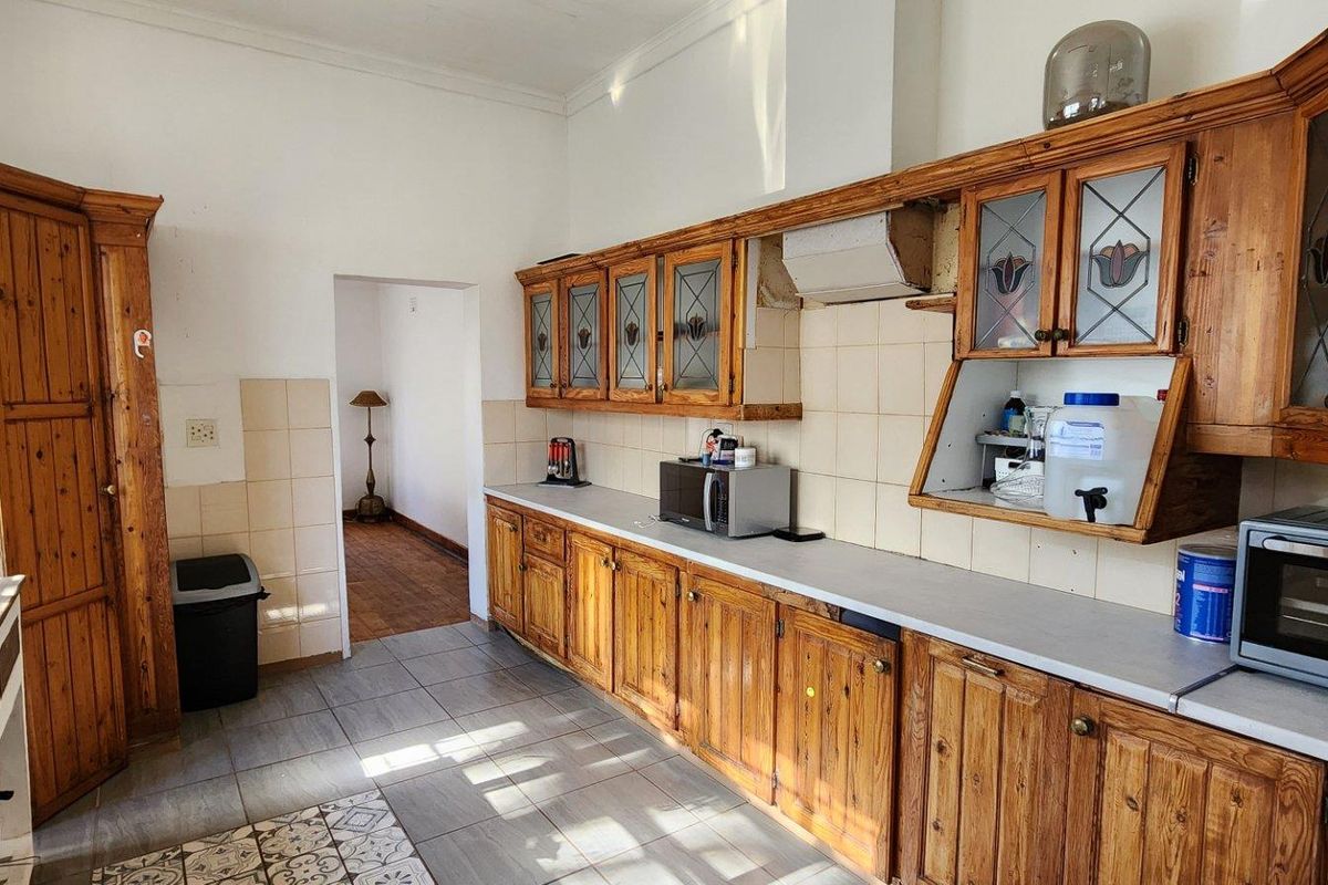 A functional kitchen featuring extensive wooden cabinetry, tiled backsplash, and tiled flooring, offering a traditional layout with potential for modern updates.