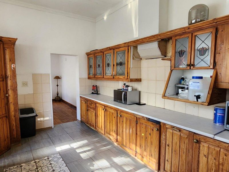 A functional kitchen featuring extensive wooden cabinetry, tiled backsplash, and tiled flooring, offering a traditional layout with potential for modern updates.