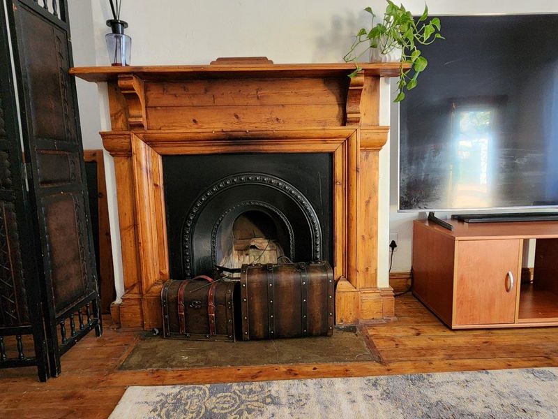 A cozy living room featuring a traditional wooden fireplace mantel with a cast iron insert and warm hardwood flooring.