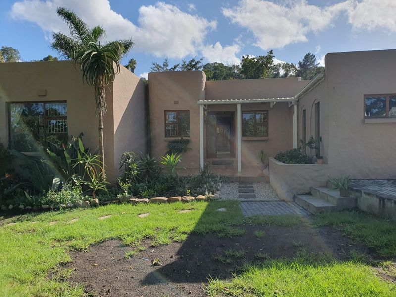 A charming single-story home featuring a stucco facade, security-barred windows, and a landscaped front garden with a paved entrance path.