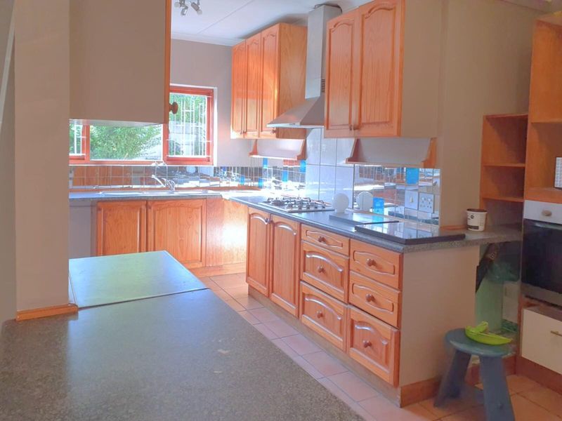 A functional kitchen featuring traditional wooden cabinetry, a gas hob with extractor fan, built-in oven, and tiled splashbacks with ample counter space.
