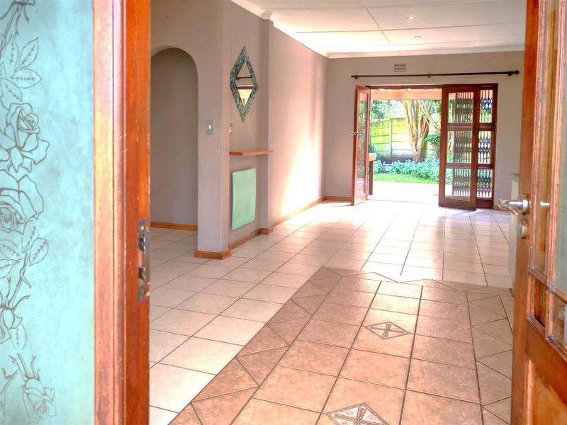 Spacious, light-filled living area featuring neutral tiled flooring, an elegant archway, and double doors providing seamless access to the rear garden.