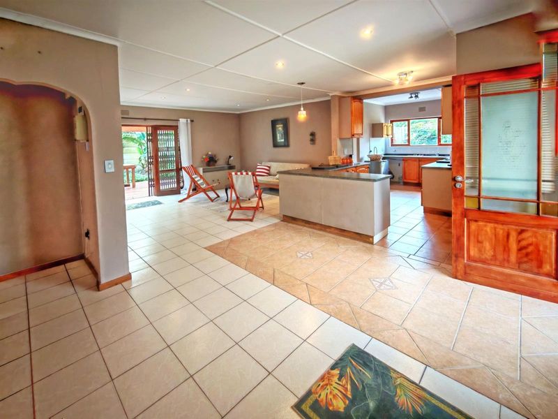 Spacious open-plan living and kitchen area featuring tiled flooring, a central kitchen island, and direct access to an outdoor patio through sliding doors.