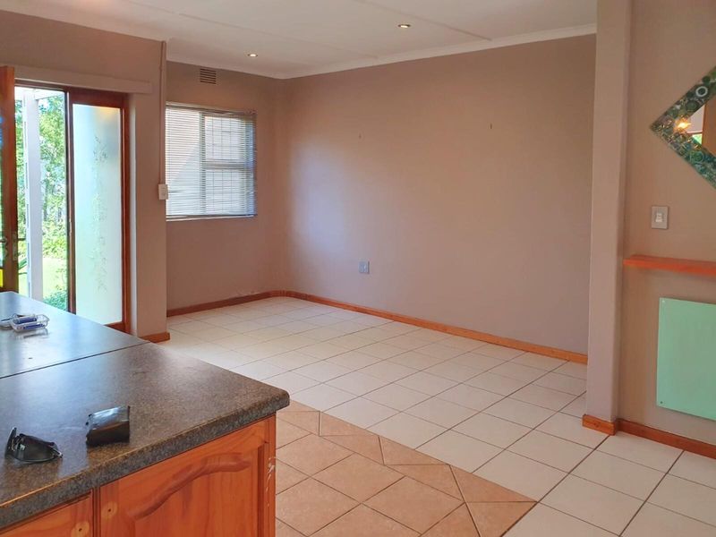 An open-plan living area featuring tiled flooring, recessed lighting, and a sliding glass door providing access to the exterior.