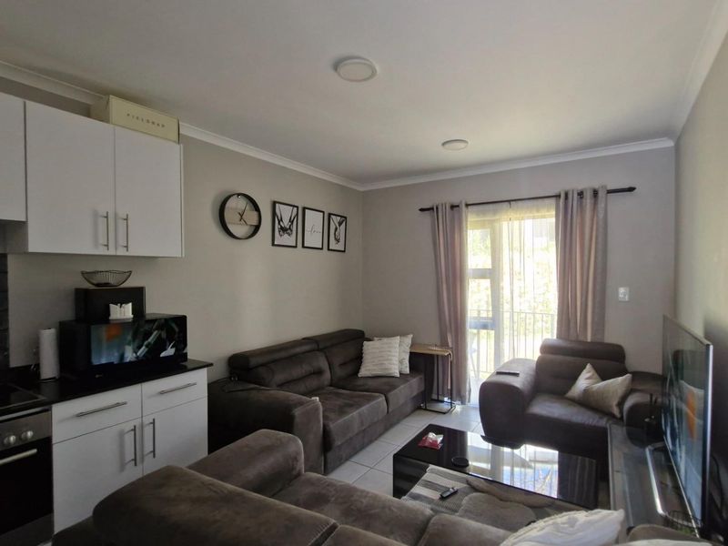 Open-plan living area featuring a compact kitchen with built-in cabinetry, electric stove, and direct access to a patio through sliding glass doors.