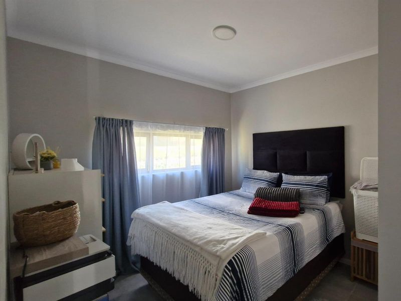A functional bedroom featuring neutral wall tones, a window with curtains, and a ceiling light fixture.