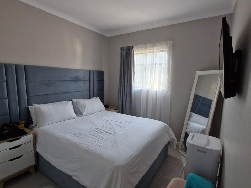 A well-maintained bedroom featuring neutral wall tones, coving, and a window with fitted curtains.