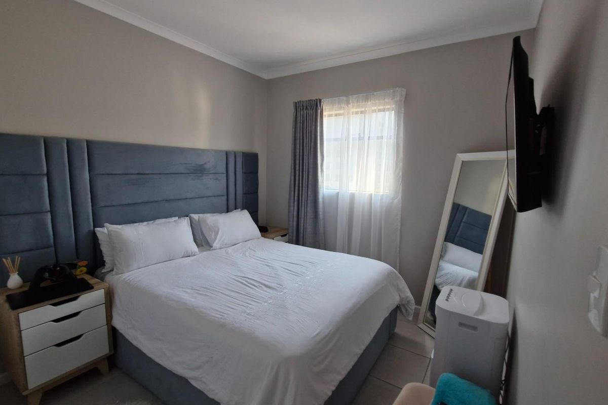 A well-maintained bedroom featuring neutral wall tones, coving, and a window with fitted curtains.