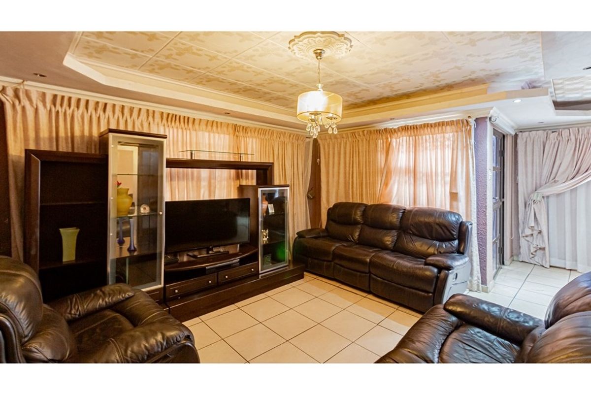 A living room featuring tiled flooring, a decorative ceiling with a central light fixture, and integrated curtain tracks.
