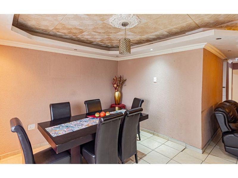 Dining area featuring tiled flooring, a decorative coffered ceiling with central pendant lighting, and textured wall finishes.