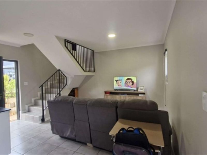 Open plan living area featuring tiled flooring, a staircase with a metal balustrade, and direct access to the exterior.