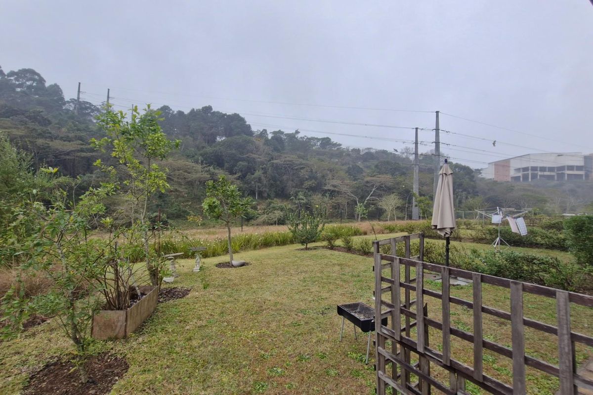 A rear garden area featuring a timber trellis and established landscaping, offering an open outlook towards the surrounding hillside.