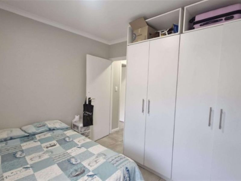 A well-maintained bedroom featuring neutral wall tones, tiled flooring, and ample built-in cupboard storage space.