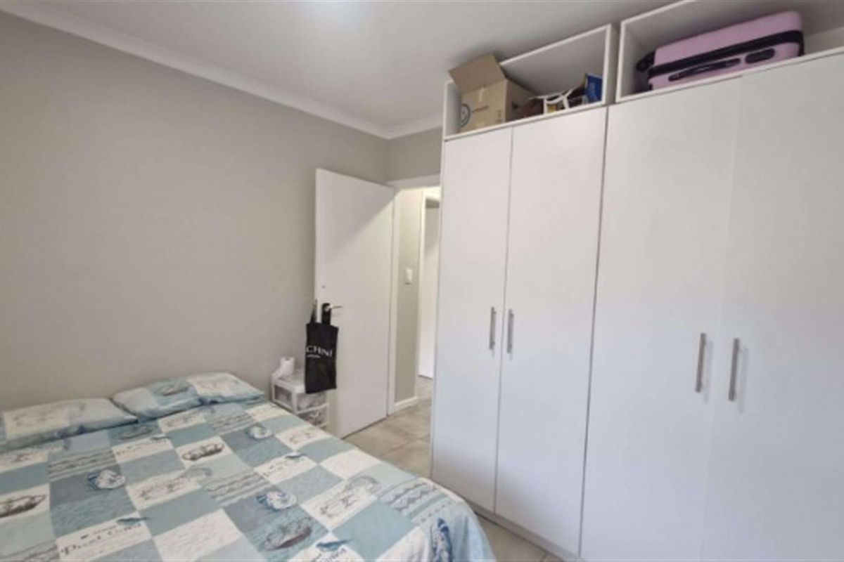 A well-maintained bedroom featuring neutral wall tones, tiled flooring, and ample built-in cupboard storage space.