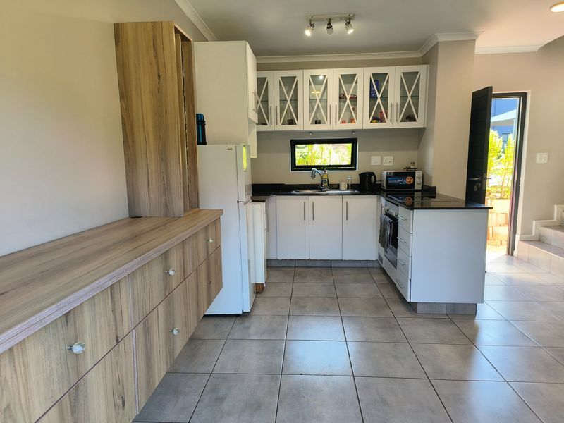 Modern kitchen featuring white and wood-grain cabinetry, granite countertops, tiled flooring, and direct access to an outdoor area.