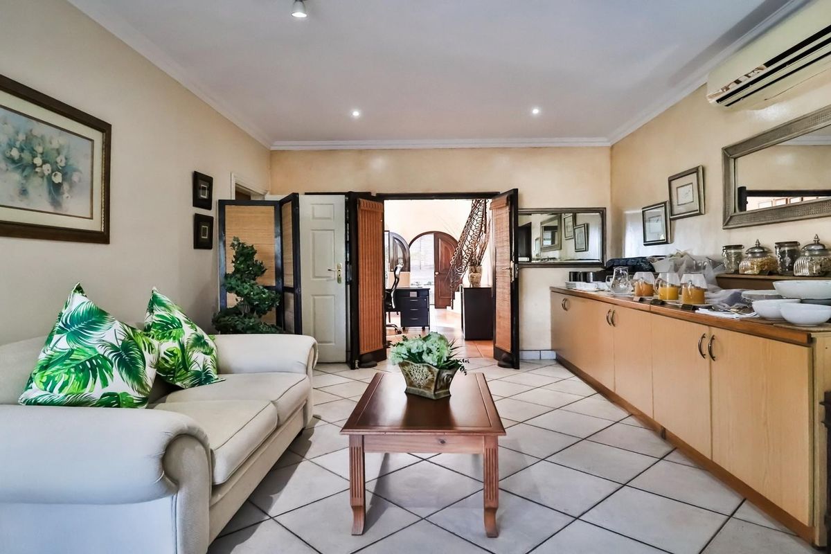 A functional guest house living area featuring tiled flooring, built-in cabinetry, and a wall-mounted air conditioning unit.