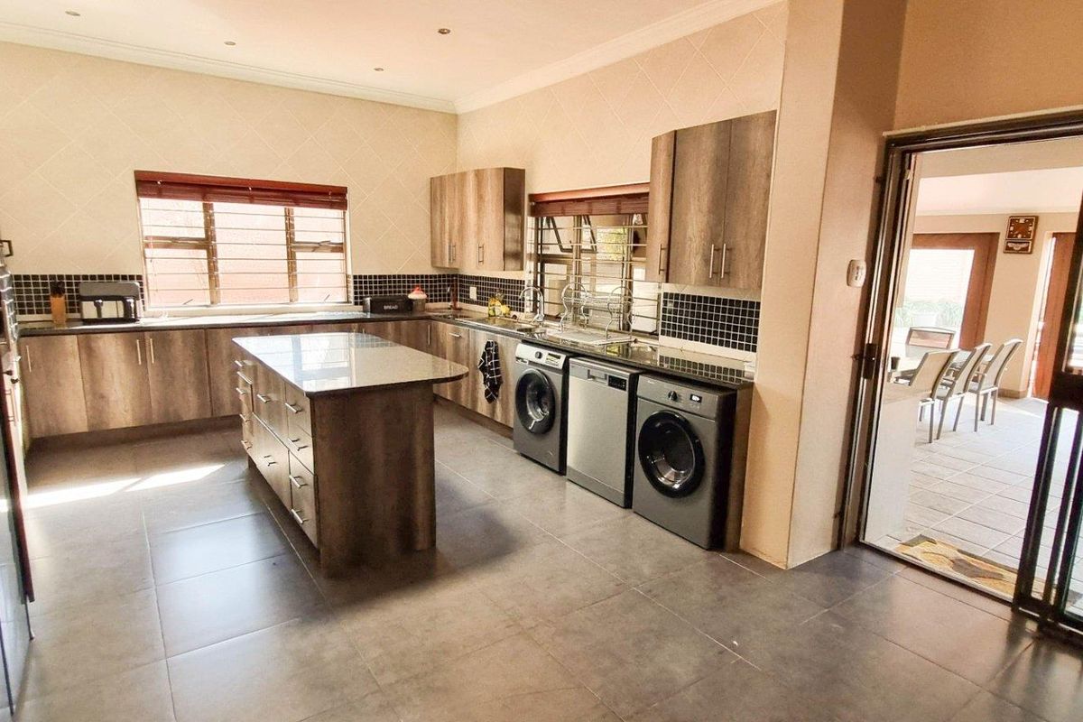 Modern kitchen featuring wood-finish cabinetry, a central island, tiled flooring, and integrated appliance spaces, with direct access to an outdoor patio area.