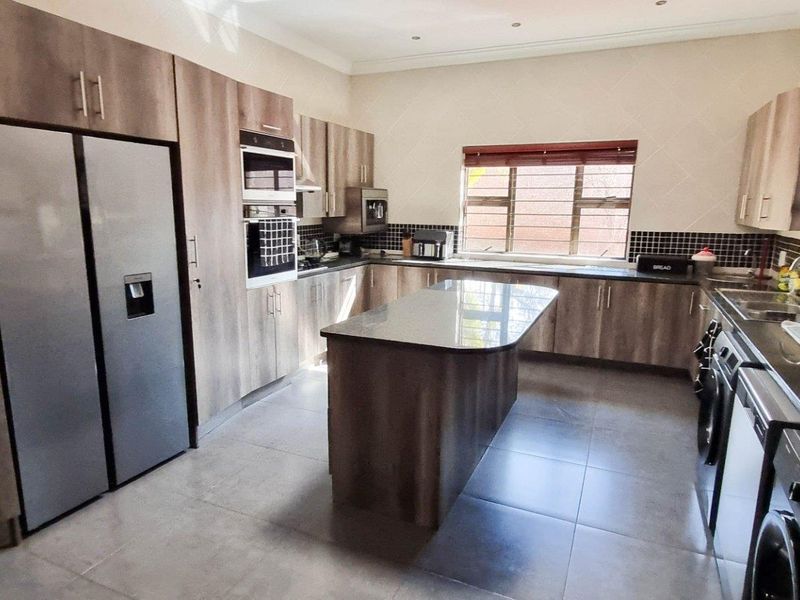 Modern kitchen featuring wood-grain cabinetry, granite countertops, a central island, built-in oven, and tiled flooring.