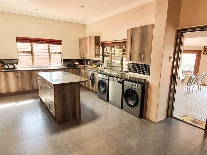 Modern kitchen featuring wood-finish cabinetry, a central island, tiled flooring, and integrated appliance spaces, with direct access to an outdoor patio area.