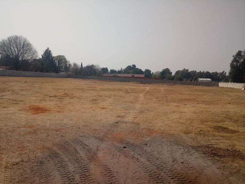 A large, undeveloped industrial plot featuring perimeter fencing and open, cleared land suitable for future development.