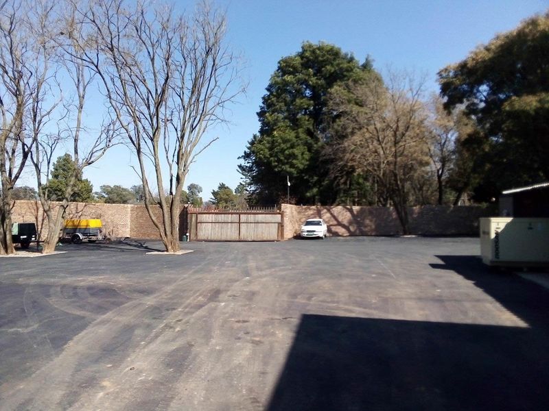 Spacious industrial yard area featuring a paved asphalt surface, secure perimeter brick walling, and gated access.