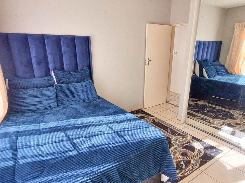A bedroom featuring tiled flooring and a large built-in wardrobe with mirrored sliding doors.
