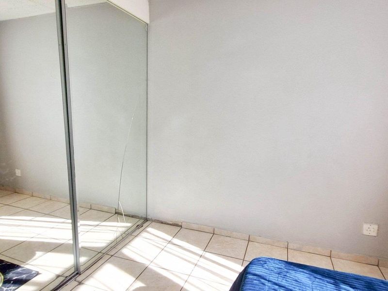 Bedroom featuring tiled flooring and a large built-in wardrobe with mirrored sliding doors.