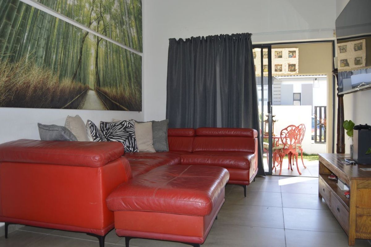 A living room featuring tiled flooring and large sliding glass doors that provide direct access to an outdoor patio area.