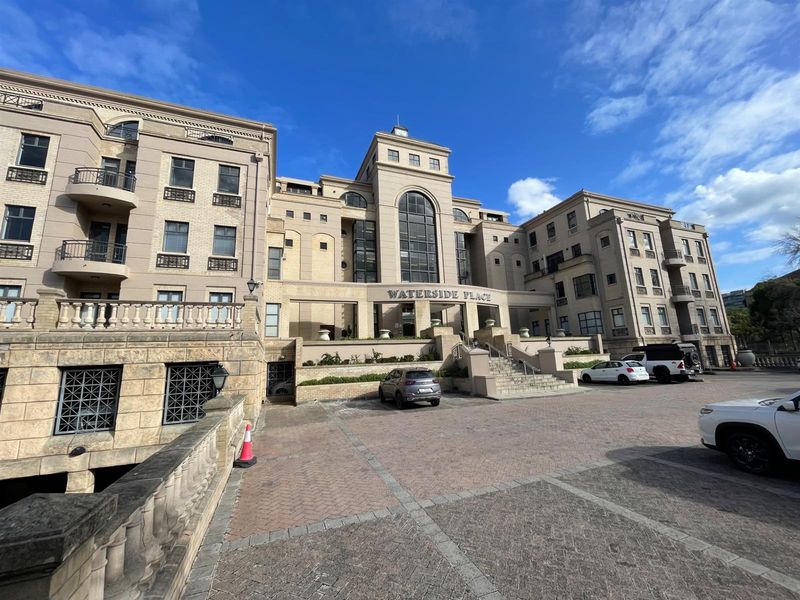 A professional exterior view of Waterside Place, showcasing its multi-story stone facade, architectural arched windows, and paved entrance area.