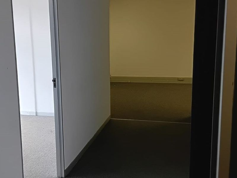 An empty office space featuring neutral carpet flooring and clean wall finishes, suitable for a professional workspace setup.