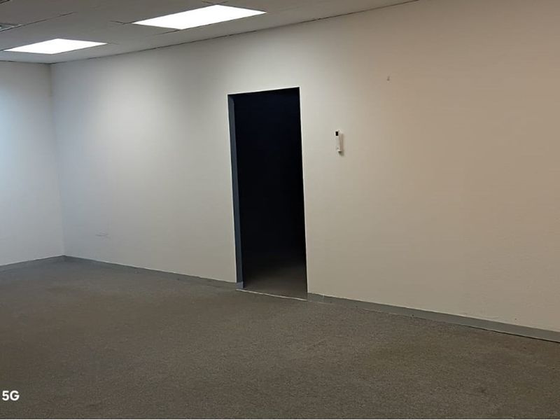 An empty, neutral-toned office space featuring recessed ceiling lighting and carpeted flooring, providing a blank canvas for professional workspace configuration.