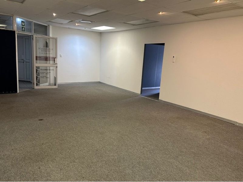 An empty, open-plan office space featuring a suspended ceiling, recessed lighting, and carpeted flooring, suitable for a variety of professional business configurations.