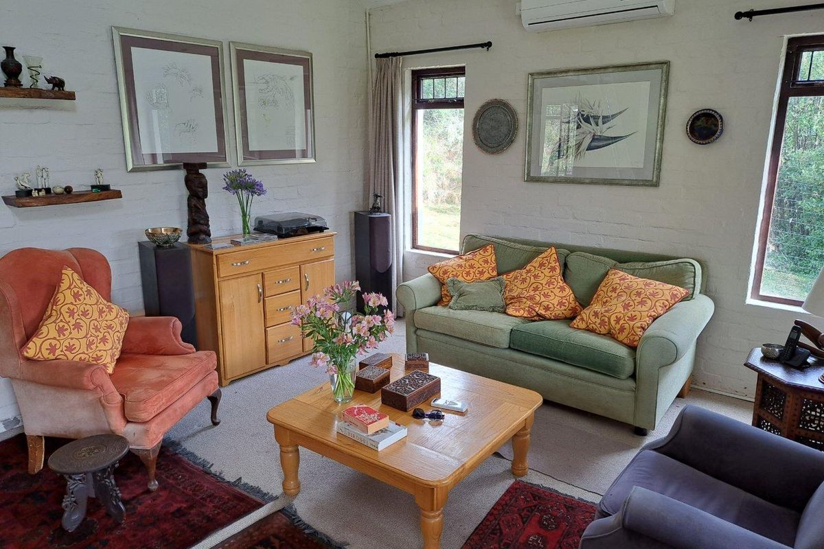 A cozy living room featuring painted brick walls, large windows, and a wall-mounted air conditioning unit.