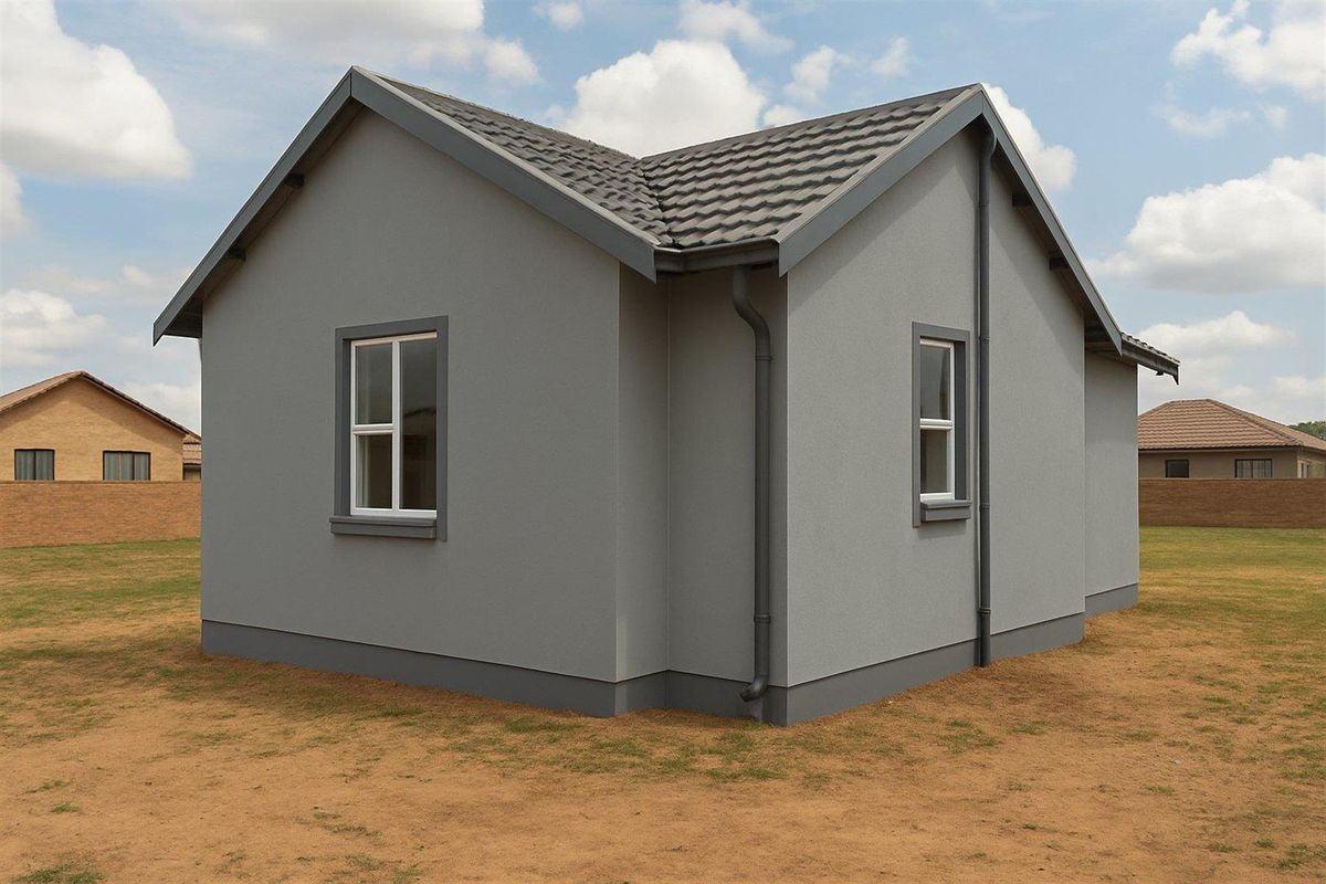 A view of the rear exterior of a modern house featuring grey rendered walls, tiled roof, and downpipes set on a clear plot.