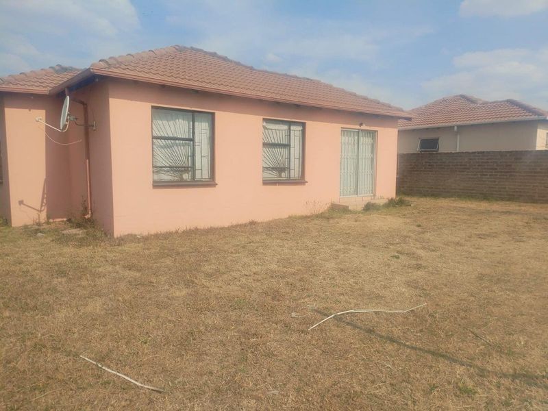 Rear view of the house featuring a tiled roof, sliding glass door, and a spacious backyard area.