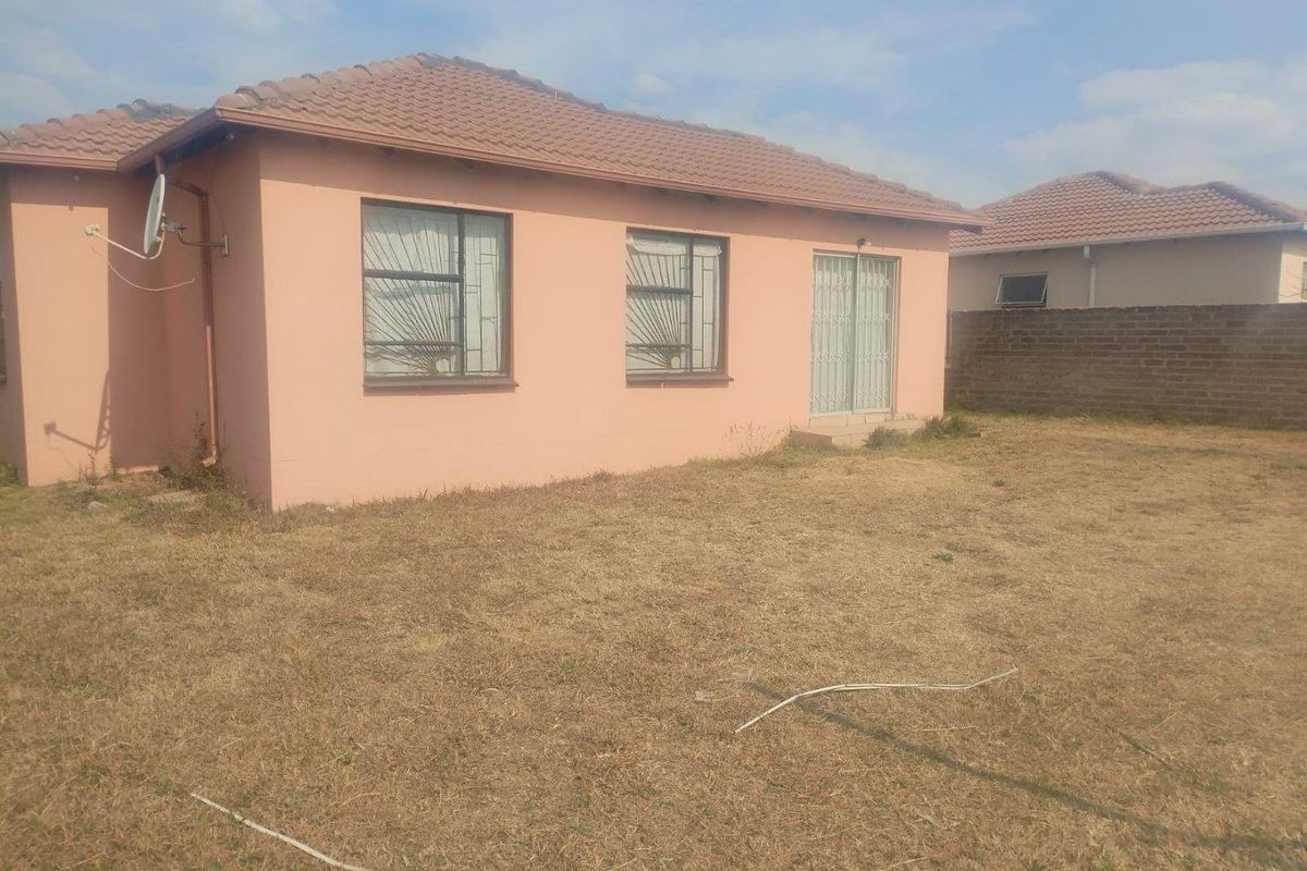 Rear view of the house featuring a tiled roof, sliding glass door, and a spacious backyard area.