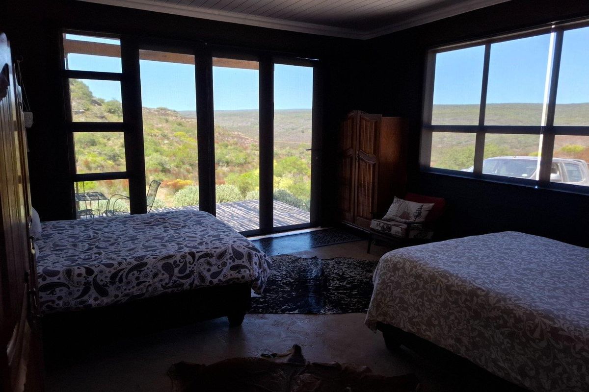 Spacious bedroom featuring large glass sliding doors that open onto a deck, offering expansive views of the surrounding natural landscape.