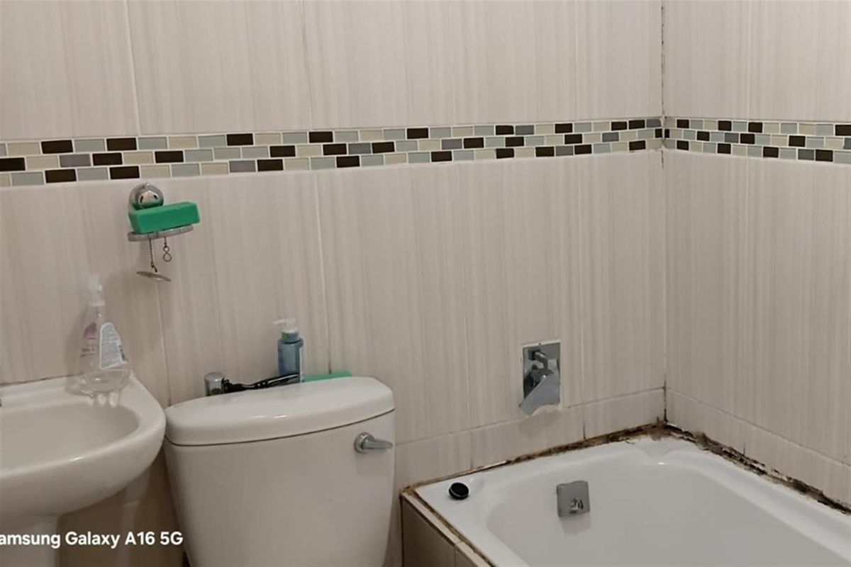 A compact bathroom featuring a bathtub, toilet, and wall-mounted basin with decorative mosaic tile accents.