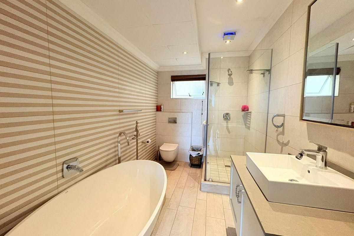 Modern bathroom featuring a freestanding bathtub, a glass-enclosed walk-in shower, a wall-mounted toilet, and a contemporary vanity with a vessel sink.