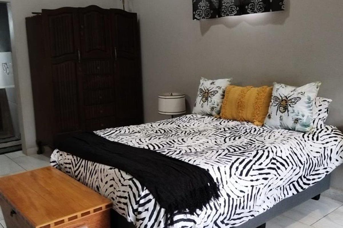 A bedroom featuring tiled flooring and a wall-mounted air conditioning unit.