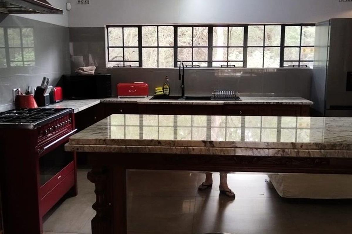 Spacious kitchen featuring granite countertops, a gas stove with extractor fan, double sink, and exposed ceiling beams with tiled flooring.