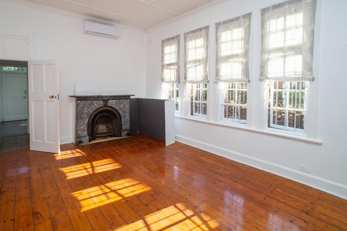 Bright and spacious room featuring polished timber flooring, a classic marble fireplace, and large sash windows allowing for ample natural light.