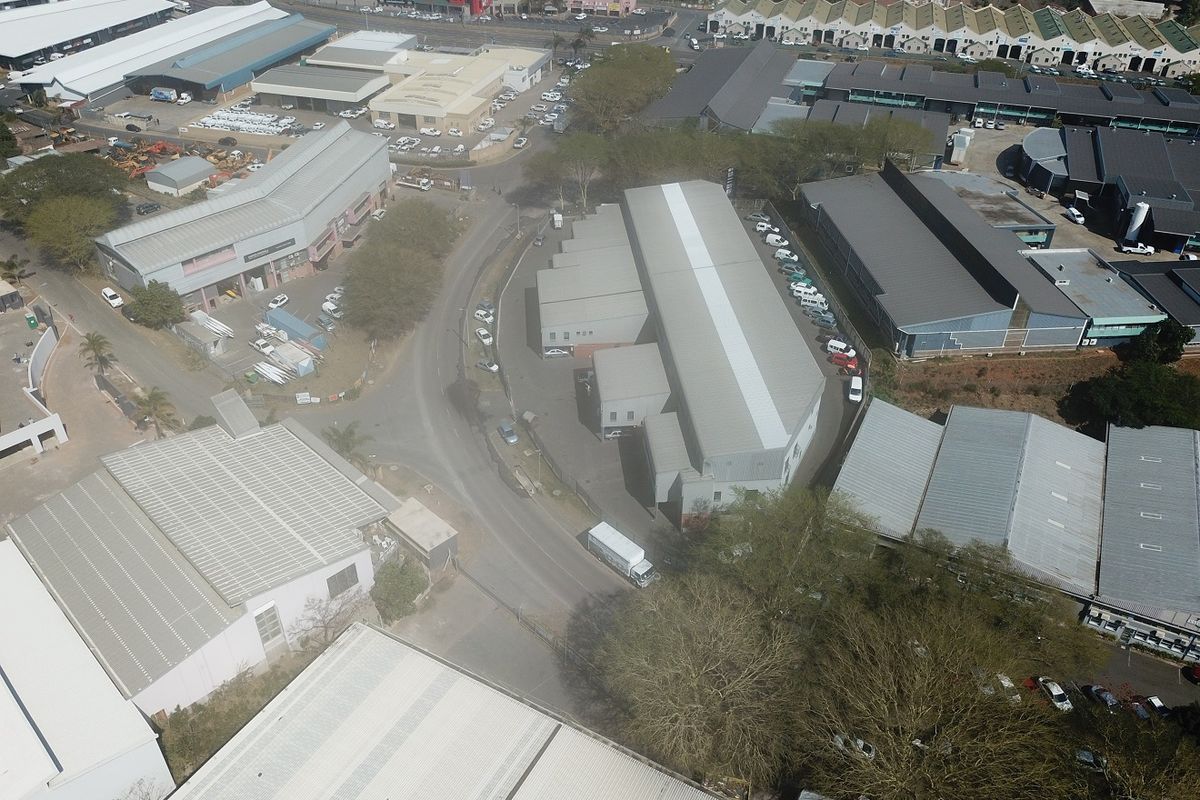 Aerial view of an industrial complex featuring multiple warehouse structures, paved access roads, and surrounding commercial properties.