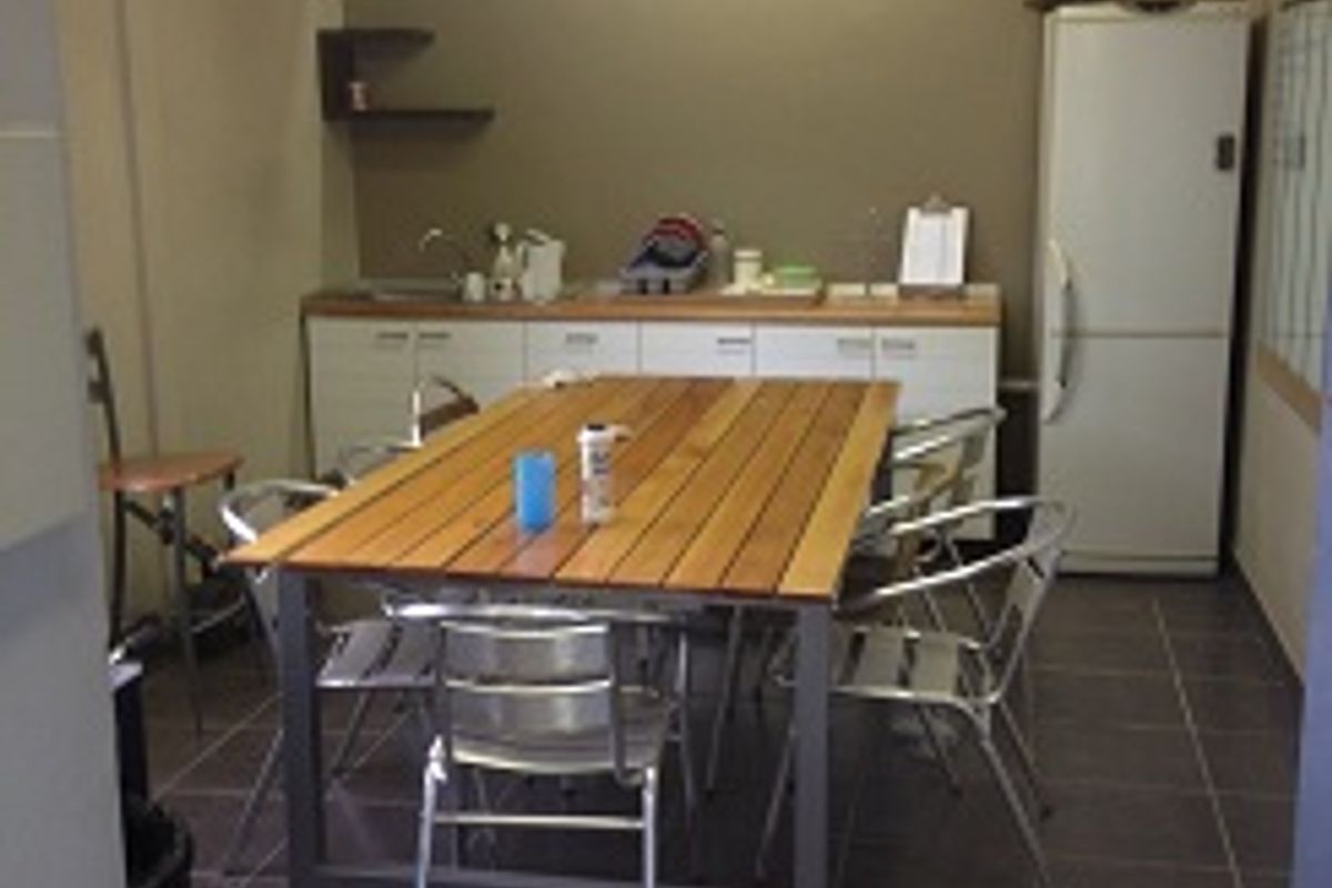 A functional breakroom or kitchenette area featuring tiled flooring, built-in cabinetry, and a ceiling fan.
