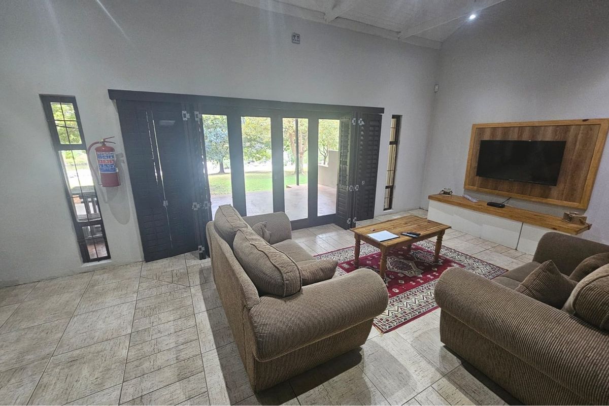 Spacious living room featuring tiled flooring, built-in wooden media unit, and large folding doors providing direct access to the outdoor patio area.