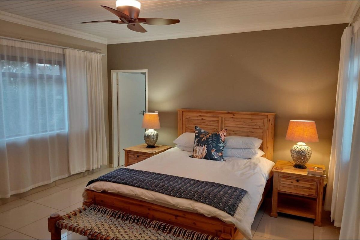 A well-maintained bedroom featuring tiled flooring, a ceiling fan, and neutral wall finishes, offering a comfortable and inviting space.