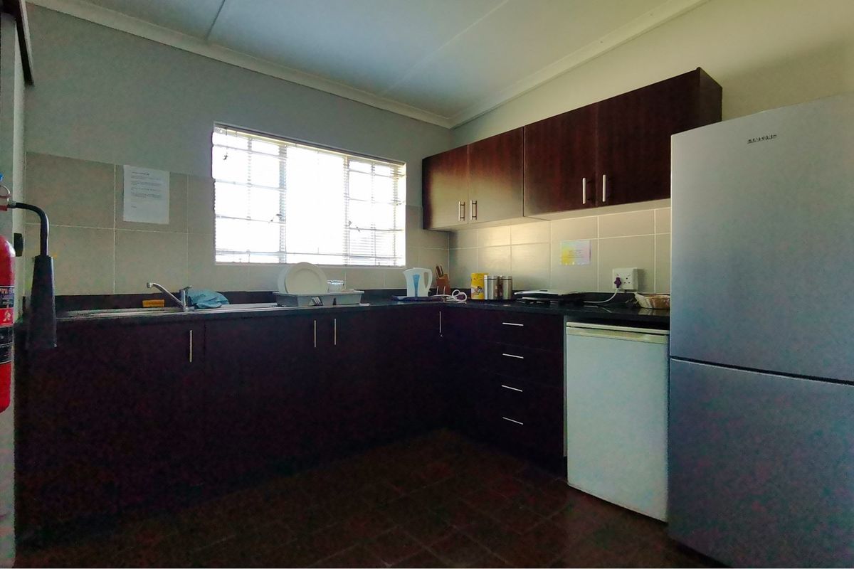 A functional kitchen featuring dark wood cabinetry, granite countertops, a tiled backsplash, and a window providing natural light.