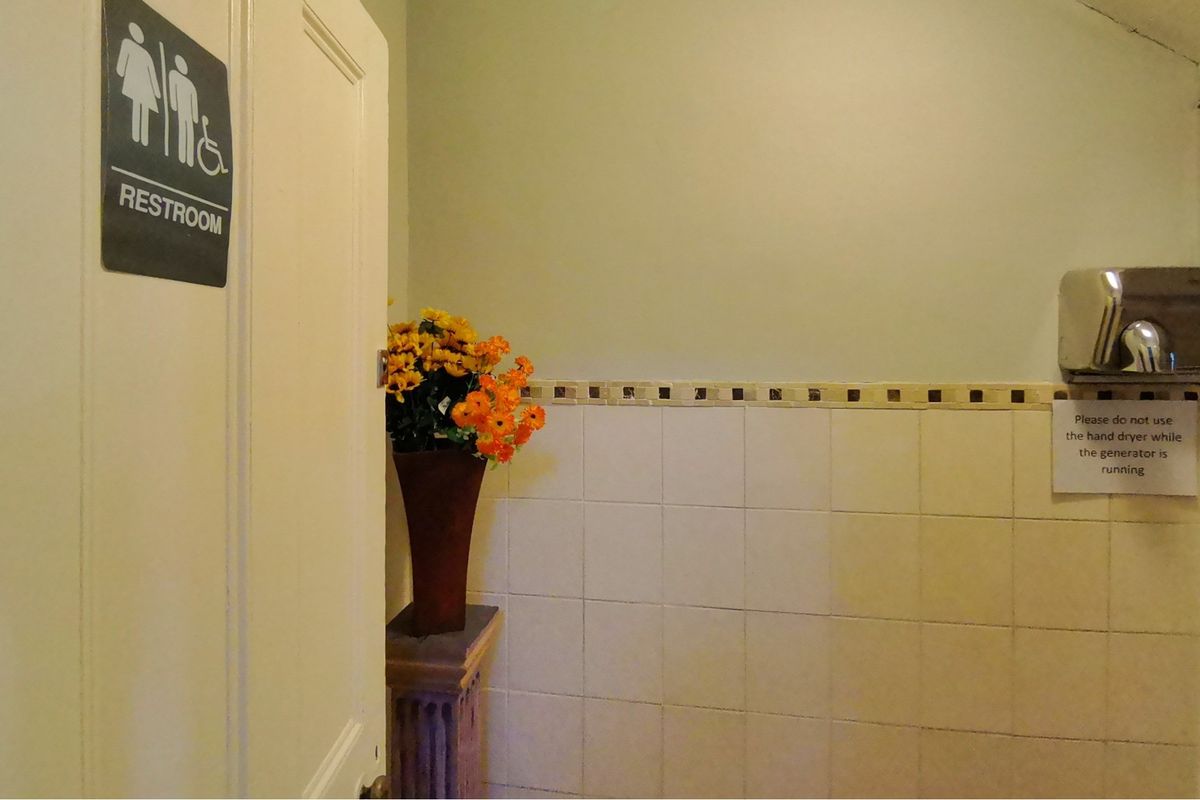 A functional restroom area featuring tiled walls and a wall-mounted hand dryer.