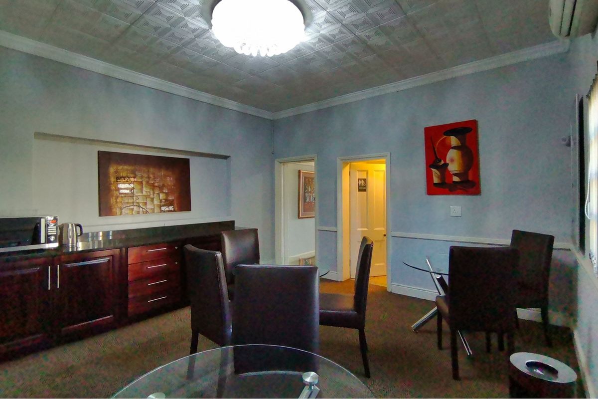 A living area featuring built-in cabinetry, decorative ceiling tiles, and coving, providing a functional space with direct access to adjacent rooms.