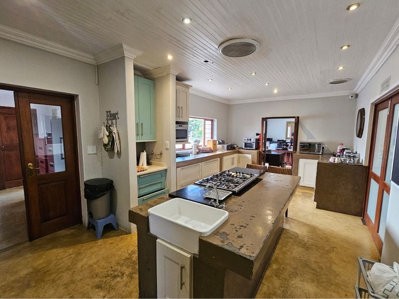 Spacious kitchen featuring a central island with a farmhouse sink and integrated gas hob, complemented by built-in cabinetry and recessed ceiling lighting.